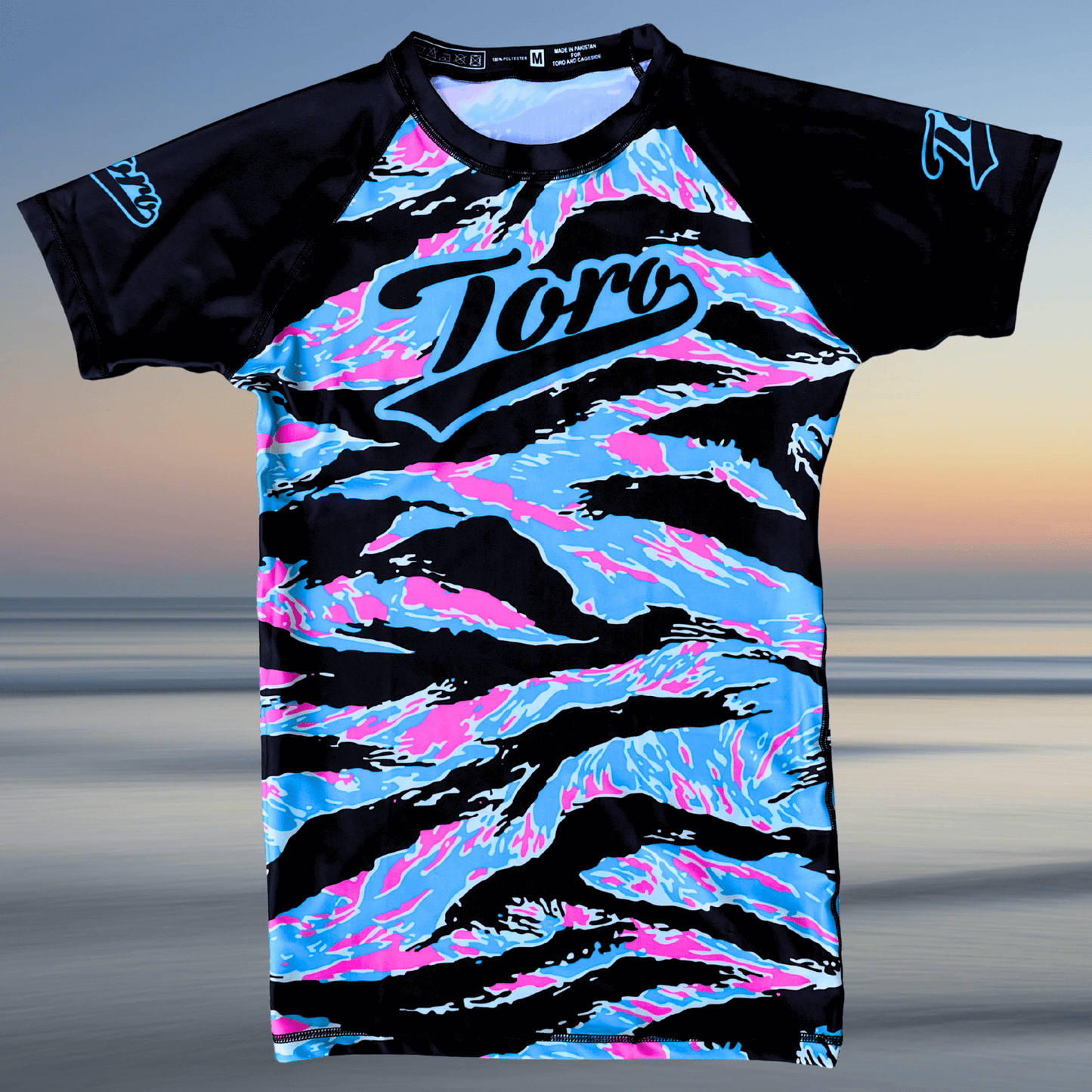 Flat lay of Toro BJJ Miami Camo rash guard with black sleeves and pastel camo pattern