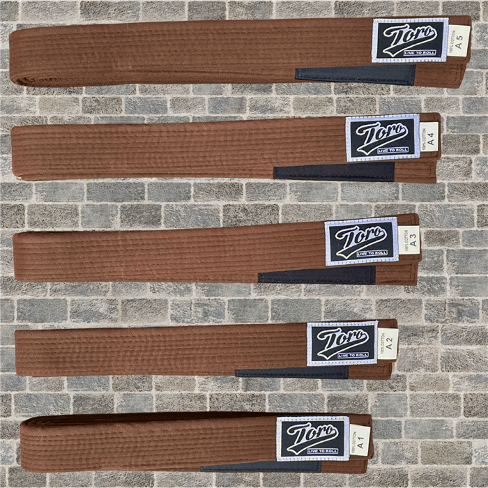 Brown BJJ belts by Toro, cotton construction with black rank bar, sizes A1 to A5 shown on stone tile background.