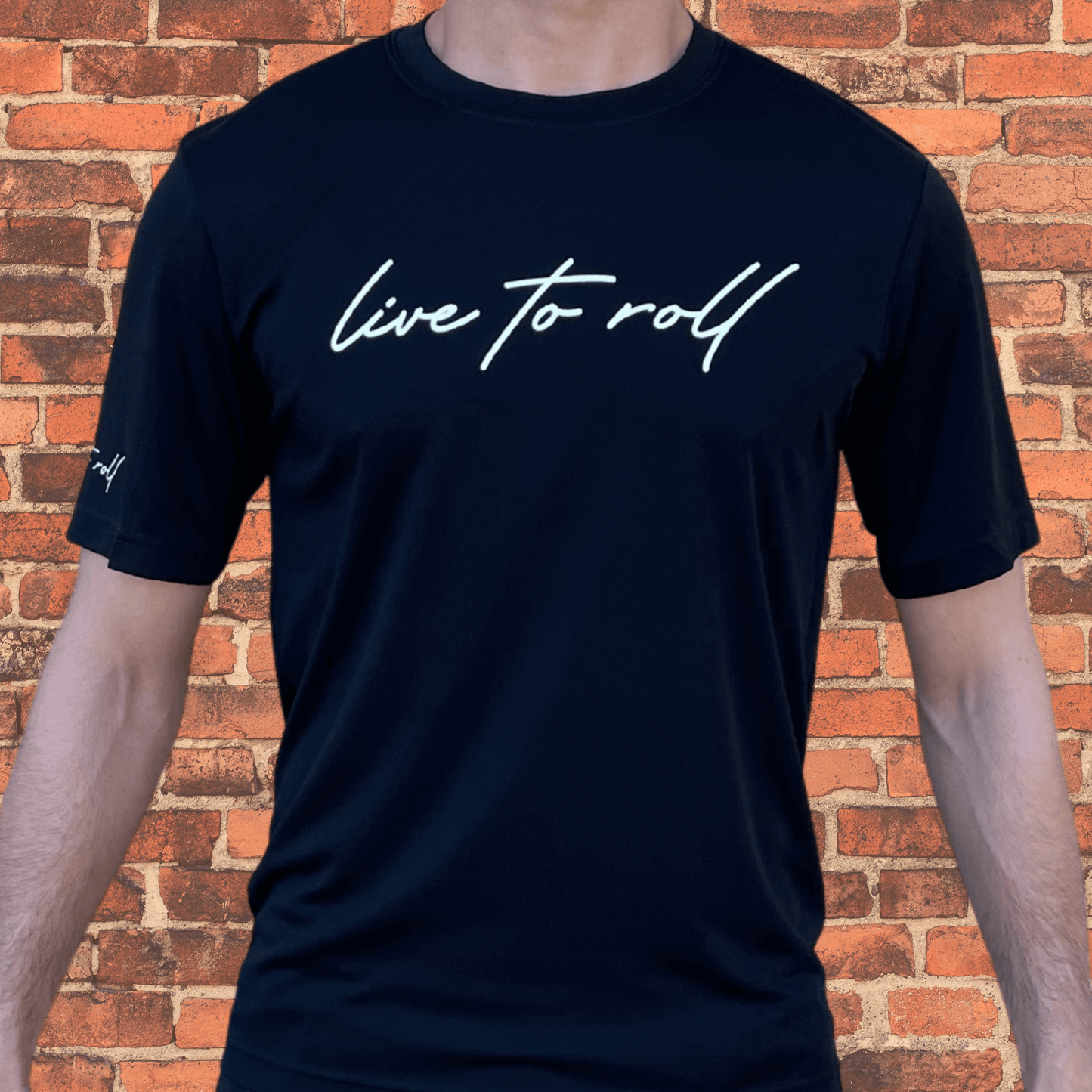 Front view of Toro BJJ Loose Fit Rash Guard in black, short sleeve, with “live to roll” text on chest and sleeve, worn by male model.