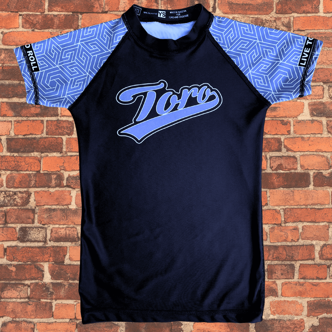 Toro BJJ Youth Gray Belt Rank Rash Guard with geometric sleeves, “Toro” script across the chest, and “Live to Roll” on both arms.