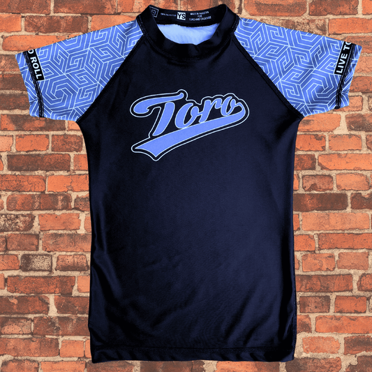 Toro BJJ Youth Gray Belt Rank Rash Guard with geometric sleeves, “Toro” script across the chest, and “Live to Roll” on both arms.