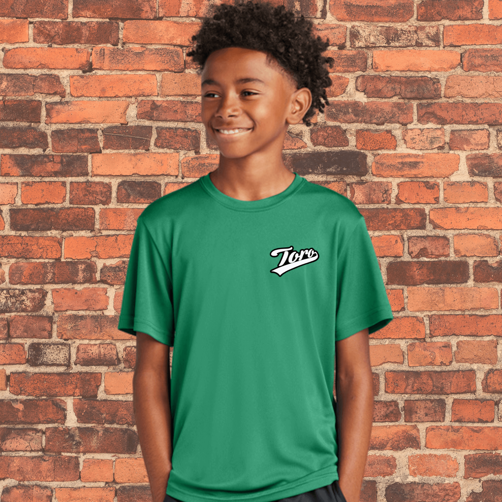 Youth BJJ athlete wearing Toro green belt rash guard in front of brick wall