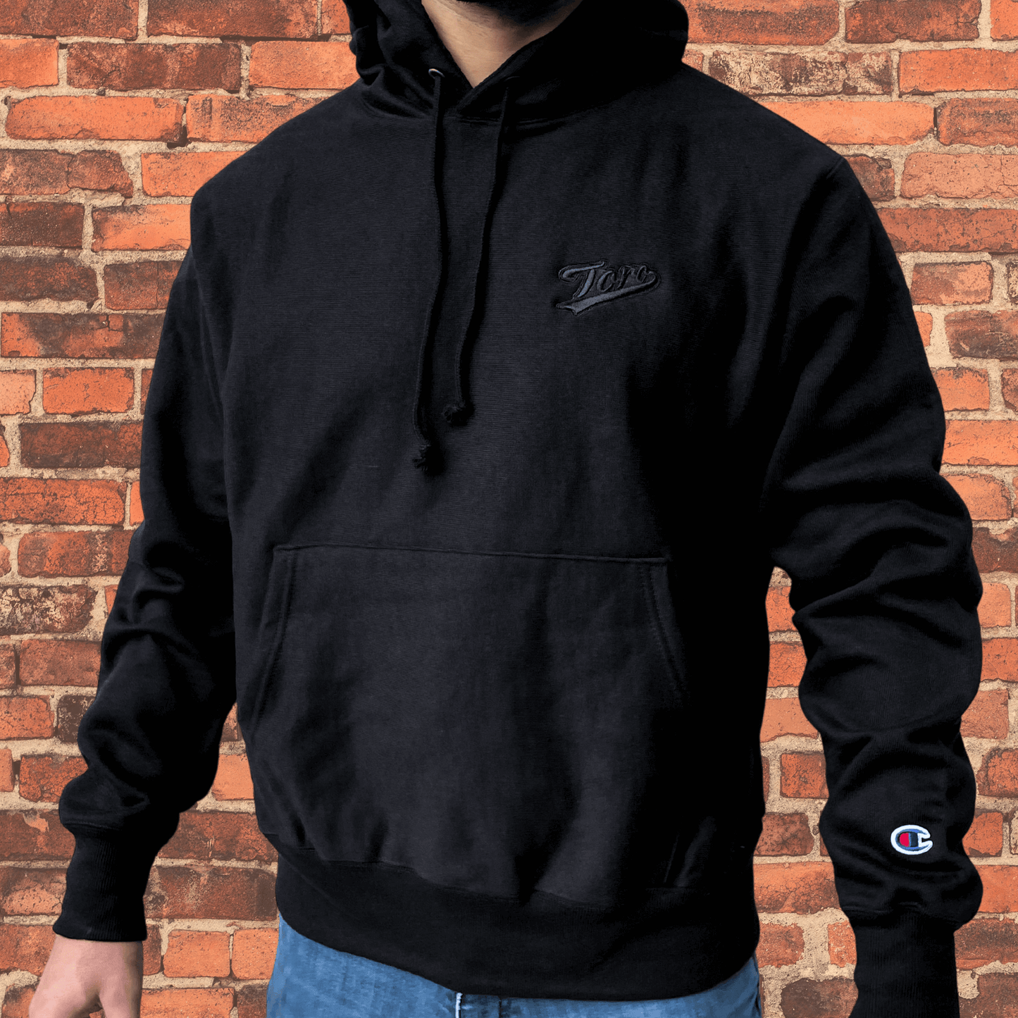 Side view of model wearing Toro x Champion Reverse Weave Hoodie black on black showing fit and cuff details.