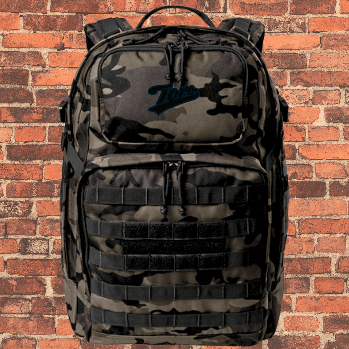 Toro Large Tactical Backpack in Dark Camo showing front pocket design and Toro logo on top valuables pocket.