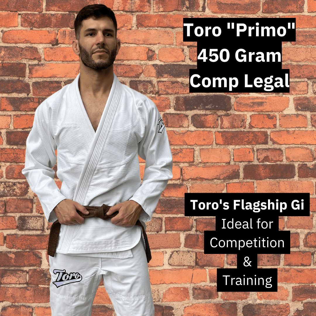 Male athlete wearing the Toro Primo white BJJ Gi with brown belt, standing against a brick wall. Overlay text highlights it as a 450 gram, comp-legal flagship gi ideal for training and competition.