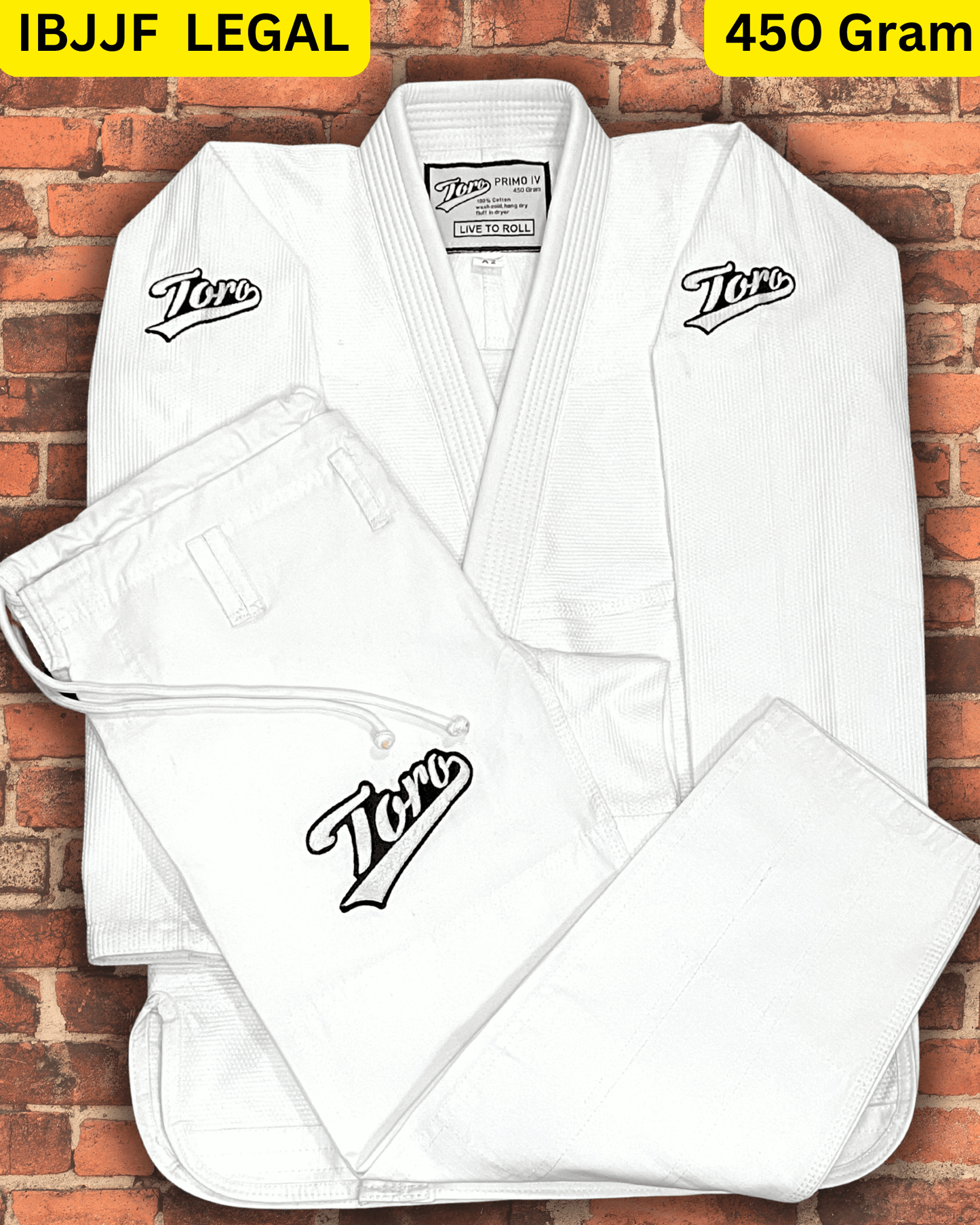 Toro Primo White BJJ Gi with 450-gram pearl weave and Live to Roll patches, IBJJF legal, folded on a brick wall background.