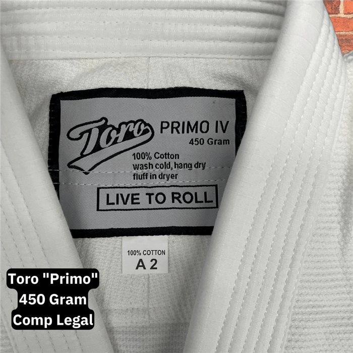 Close-up of the inner label on the Toro Primo White BJJ Gi showing 450 gram weight, 100% cotton material, and “Live to Roll” slogan, with visible A2 size tag and collar stitching detail.