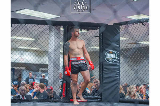 Tommy Little T Cuozzi in the MMA cage wearing Cageside shorts and red gloves during a fight event in front of a packed crowd