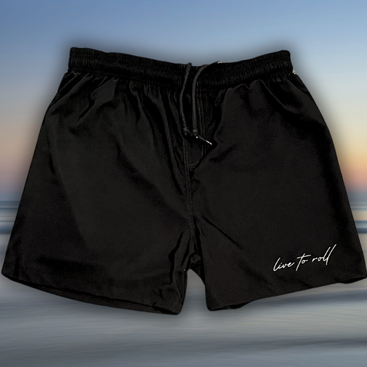 Black NoGi fight shorts with “Live to Roll” script logo on leg, laid flat with drawstring waistband, Toro BJJ minimalist training shorts