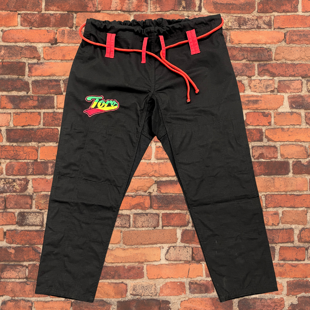 Black BJJ Gi pants by Toro feature a Rasta-colored logo and red drawstrings for a secure fit.