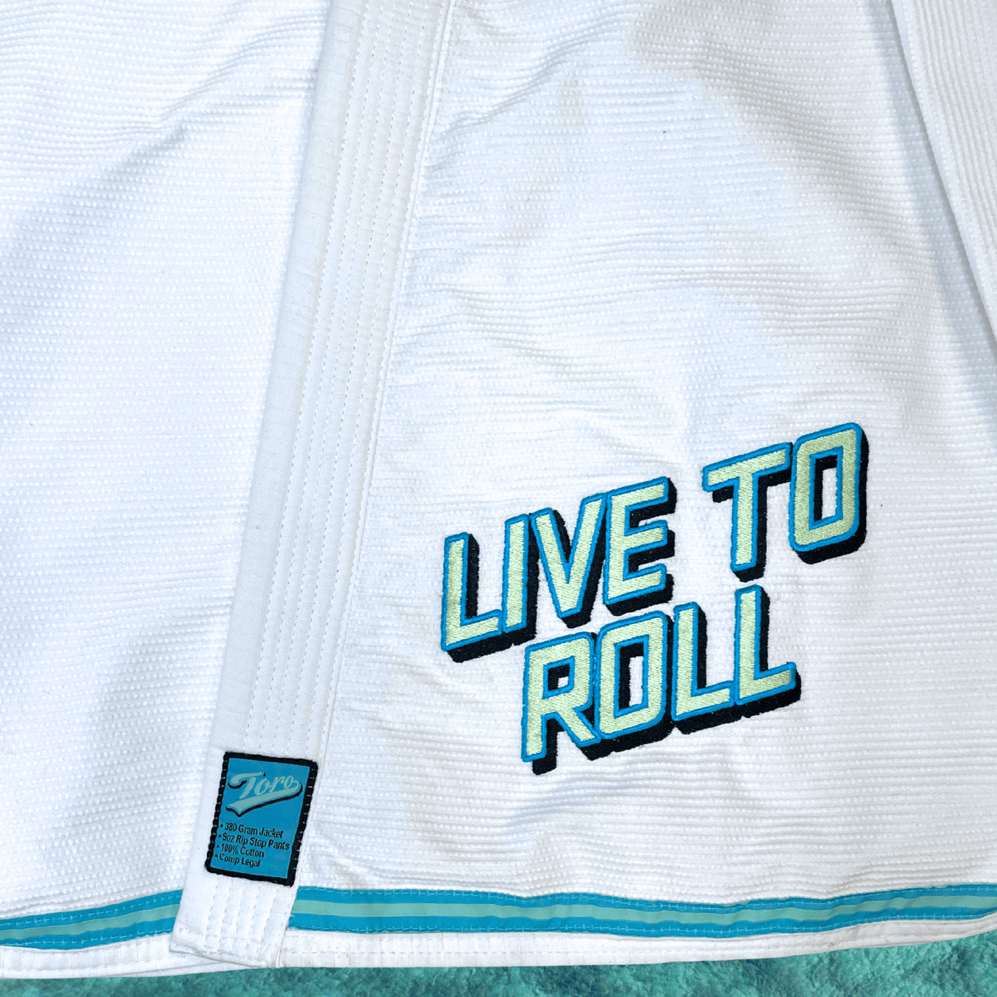 Front detail of white Good Vibes BJJ Gi with Live to Roll embroidery and Toro patch