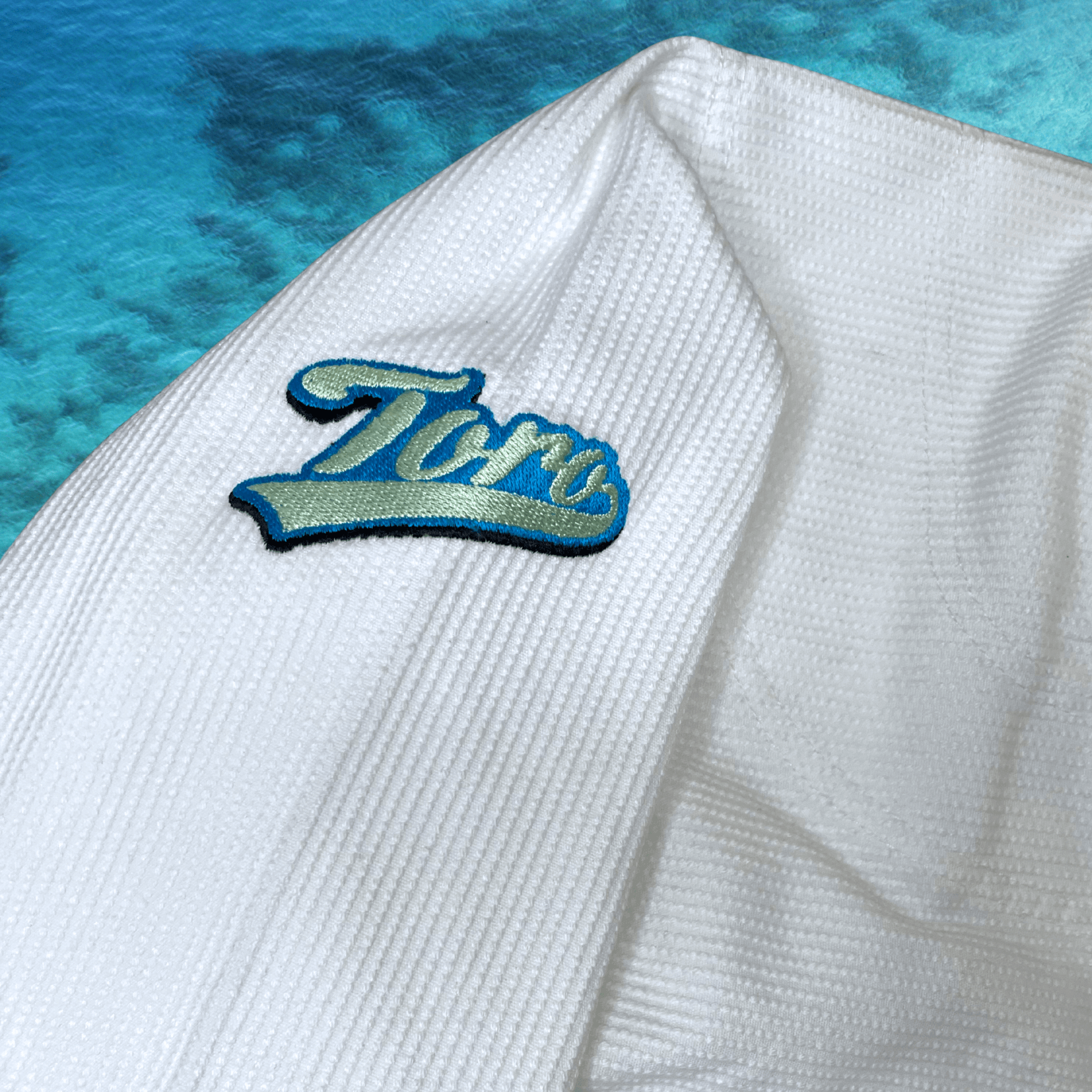 Close-up of Toro logo embroidery on the shoulder of the white Good Vibes BJJ Gi