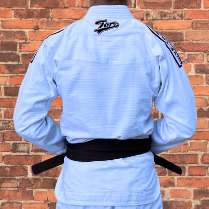 Back view of a Brazilian Jiu-Jitsu practitioner wearing a white Toro BJJ gi with a brown belt, showcasing the embroidered Toro logo on the upper back and shoulder patches. The gi offers a lightweight, durable design ideal for training and competition.