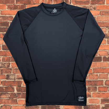 Toro Youth Black Label Long Sleeve BJJ Rash Guard laid flat on brick background showing front design