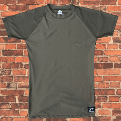 Toro Youth Black Label Olive Drab BJJ Rash Guard laid flat on brick background showing short sleeve design