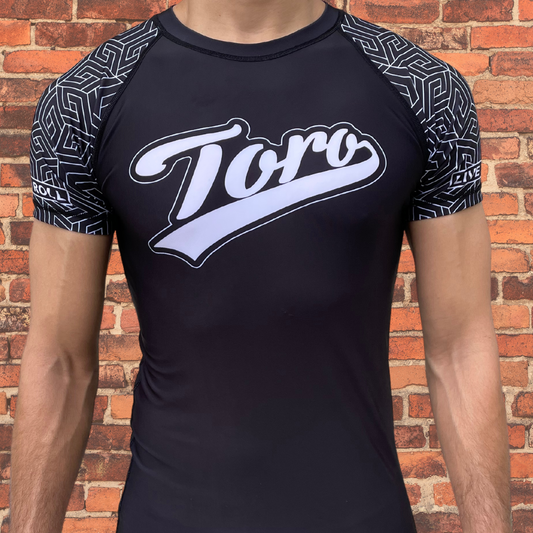 Man wearing a Toro black belt ranked rash guard with black geometric sleeve design.