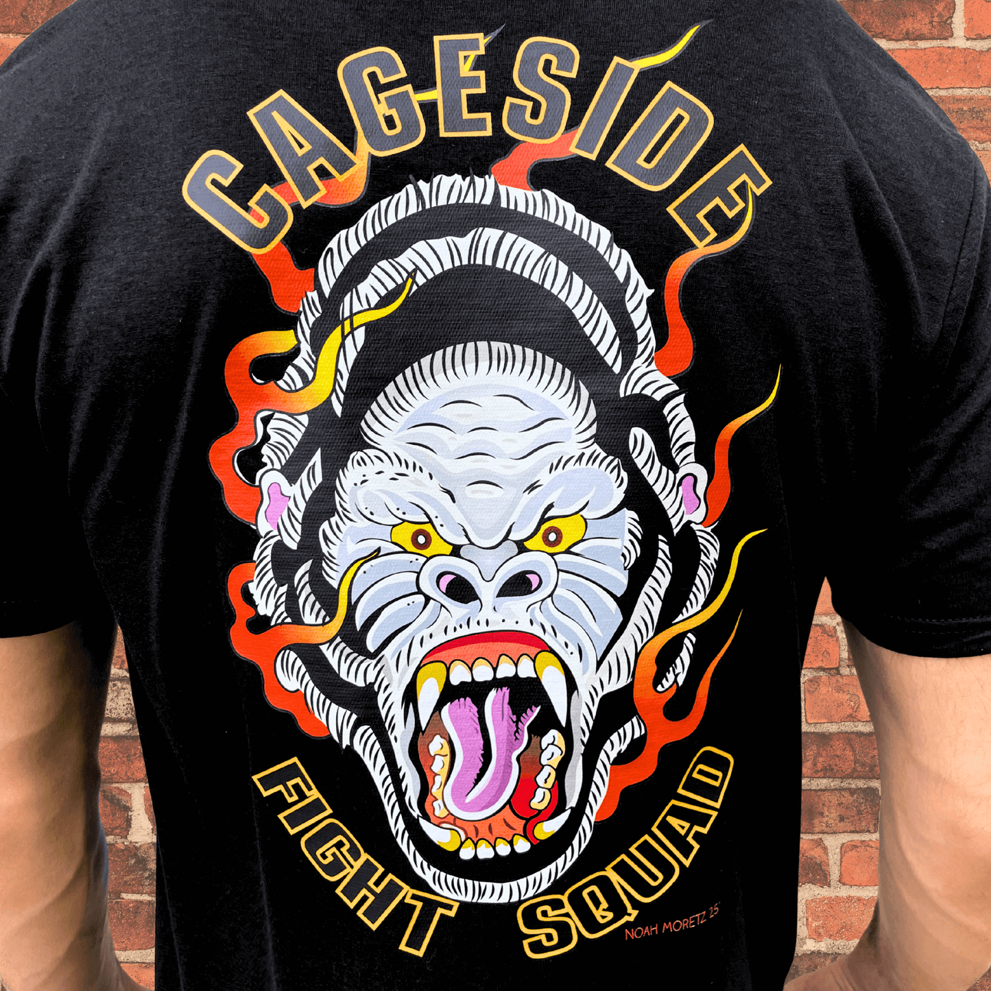 Close-up of back graphic on black Cageside Fight Squad shirt featuring a flaming gorilla illustration with bold text