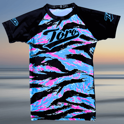 Laid flat Miami Camo BJJ rash guard with vibrant pink, blue, and black camo design