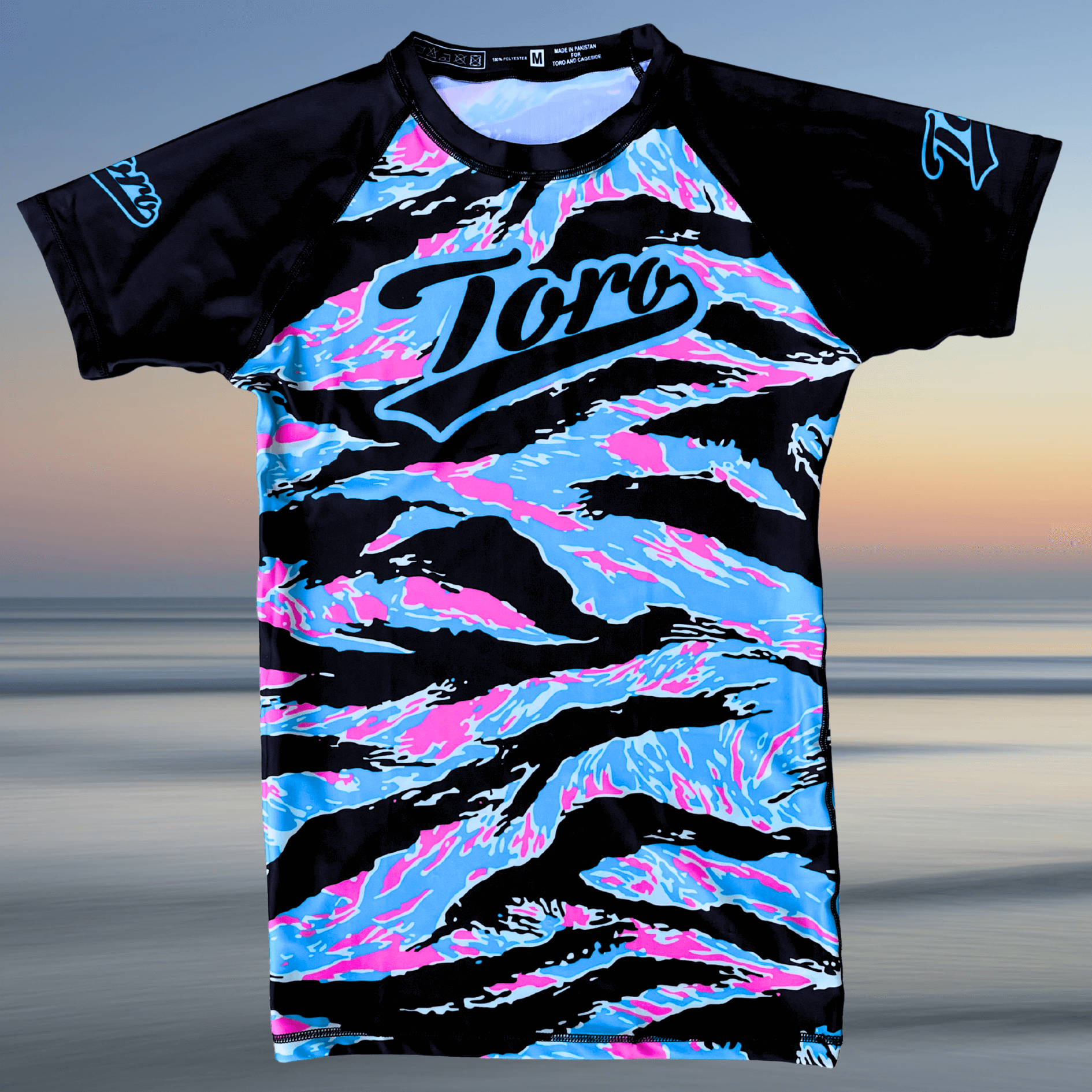 Flat lay of Toro BJJ Miami Camo rash guard with black sleeves and pastel camo pattern