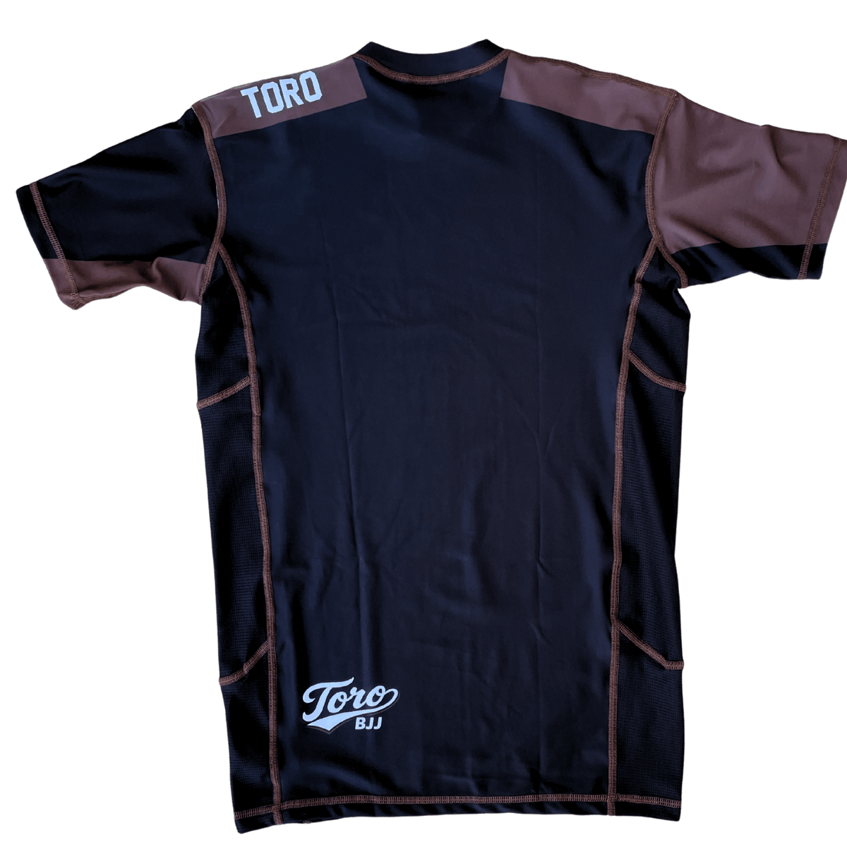 Back view of Toro 2027 brown belt rash guard with brown shoulder panels and a white lower back logo