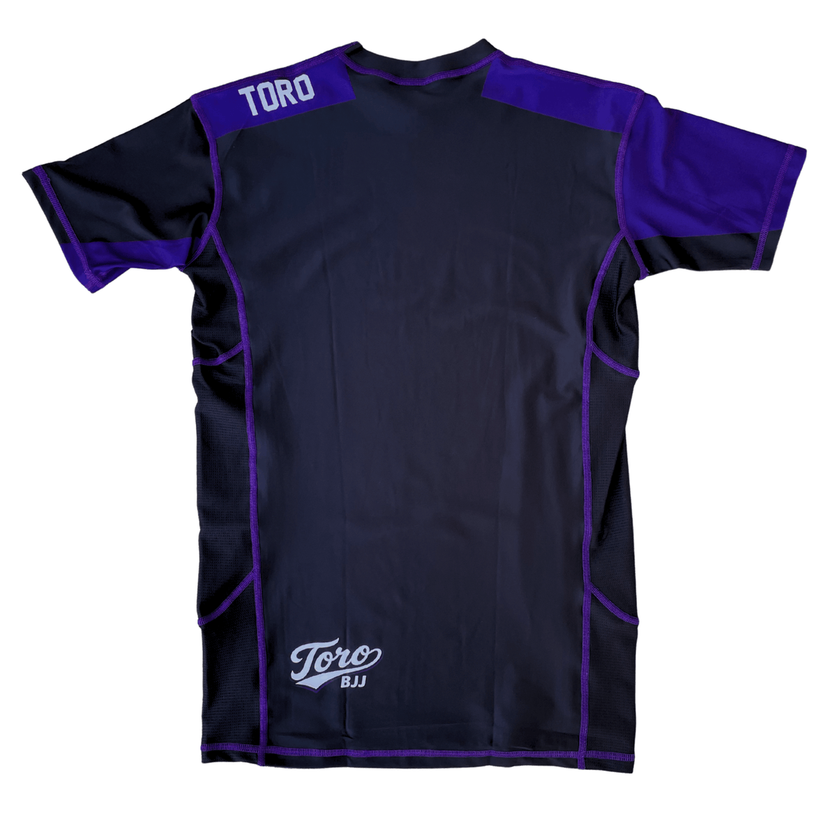 Back view of Toro 2027 purple belt rash guard with purple shoulder panels and a white lower back logo