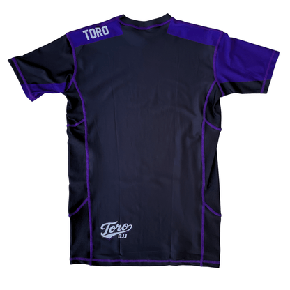 Back view of Toro 2027 purple belt rash guard with purple shoulder panels and a white lower back logo