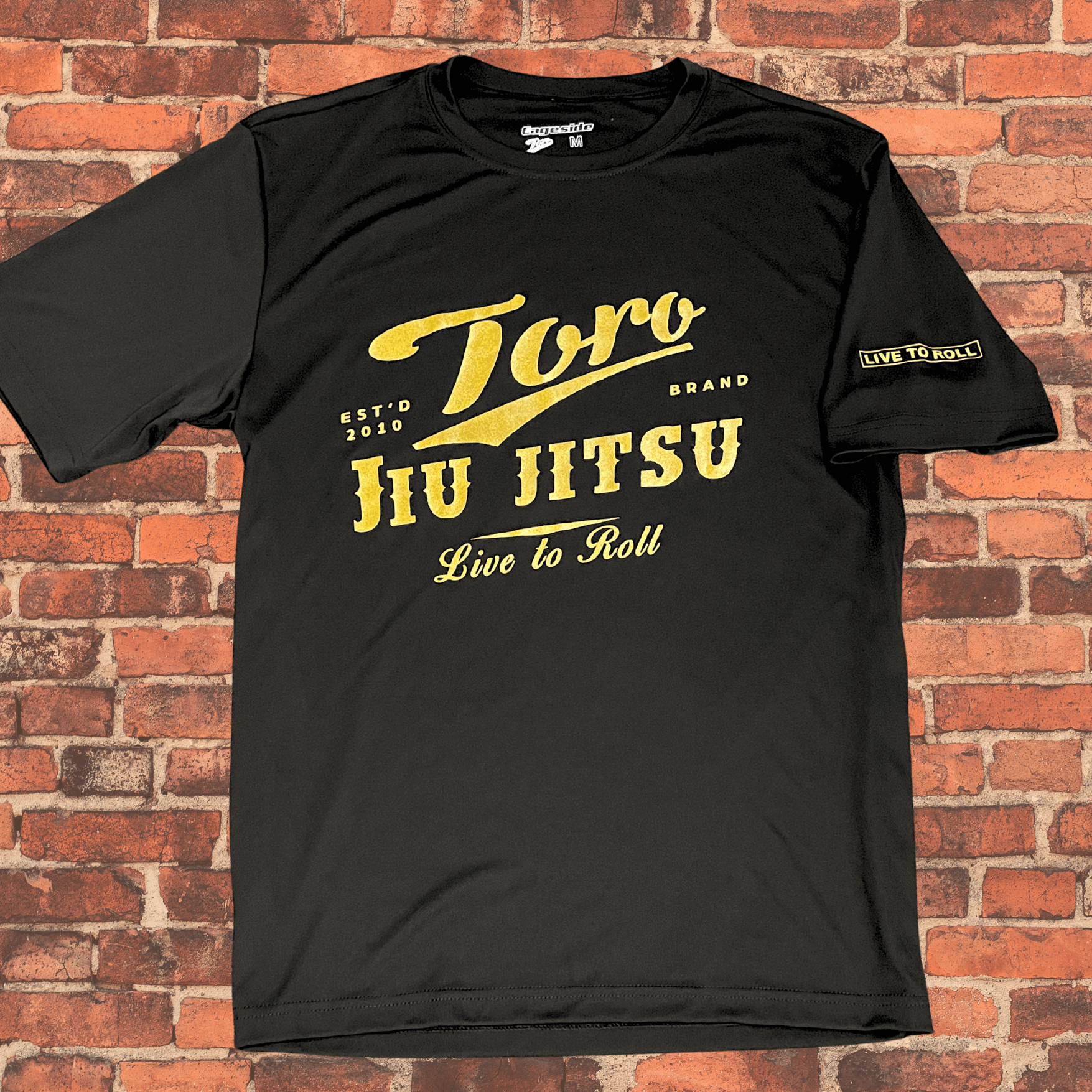 Loose-Fit Toro BJJ Classic Rash Guard laid flat with gold Jiu-Jitsu logo and Live to Roll sleeve detail