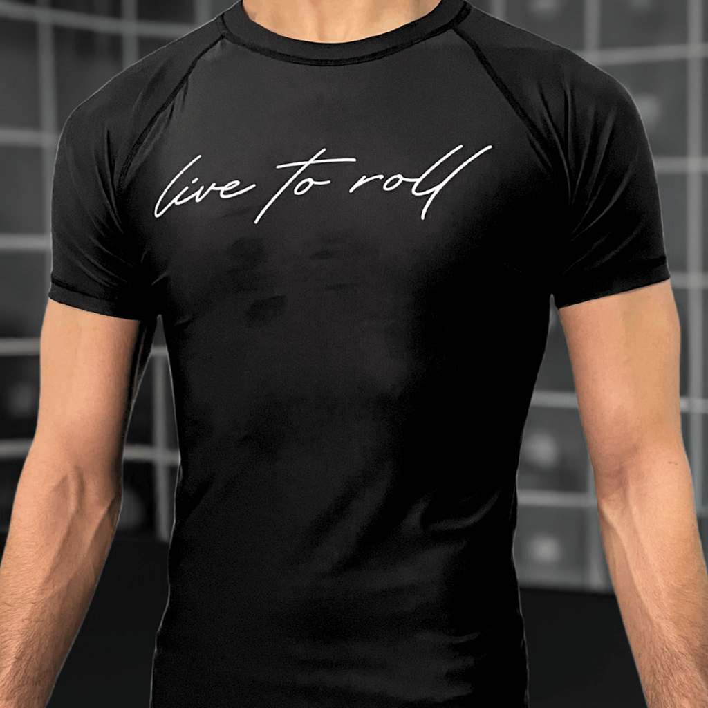 Black short sleeve rash guard with “live to roll” text on chest, worn by male model, for NoGi Jiu-Jitsu training.