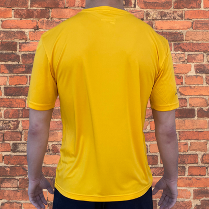 Back view of Toro BJJ Loose Fit Rash Guard in gold, plain back with subtle logo on neckline, short sleeves, worn by male model.