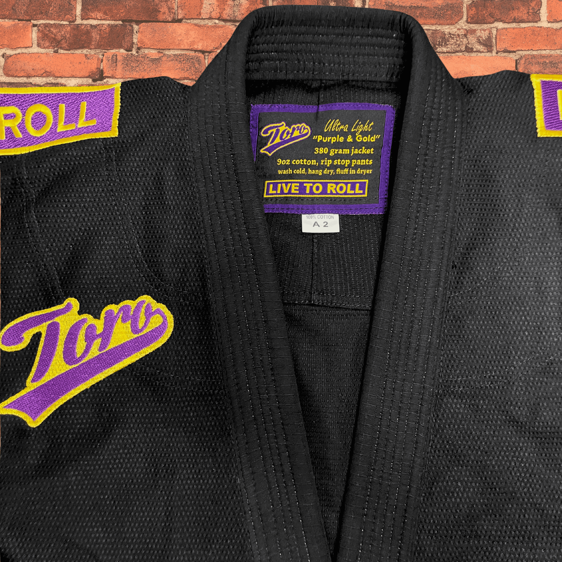 Closeup of black BJJ Gi collar with Toro purple and gold patch and Live to Roll label, IBJJF approved Purple & Gold Gi