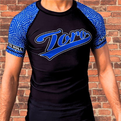 Toro BJJ Blue Belt Ranked Rash Guard with black body, blue patterned sleeves, large Toro logo on chest, Live to Roll patch on sleeve.