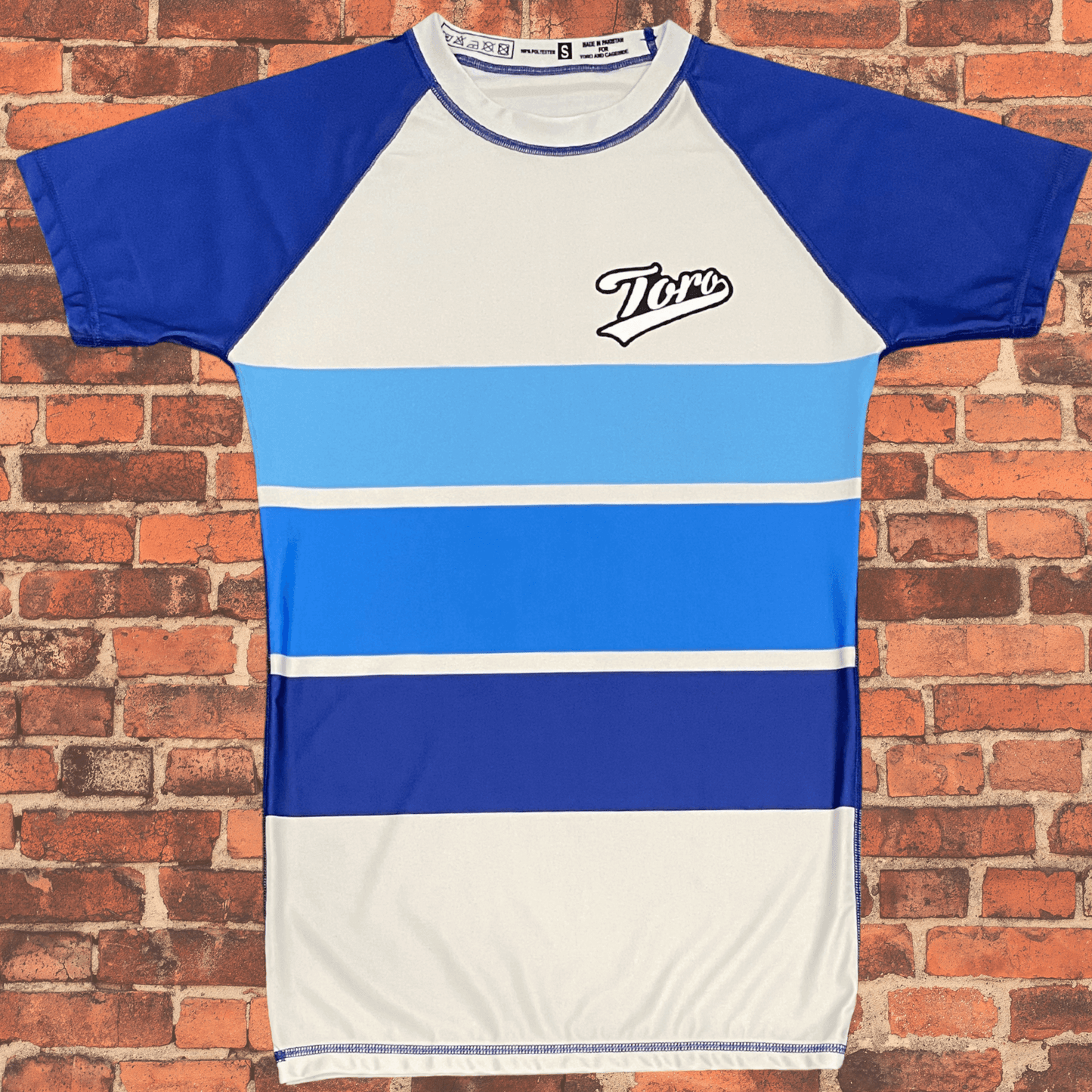 Toro BJJ Sand Shark Rash Guard with blue ocean stripe design and Toro logo on chest.