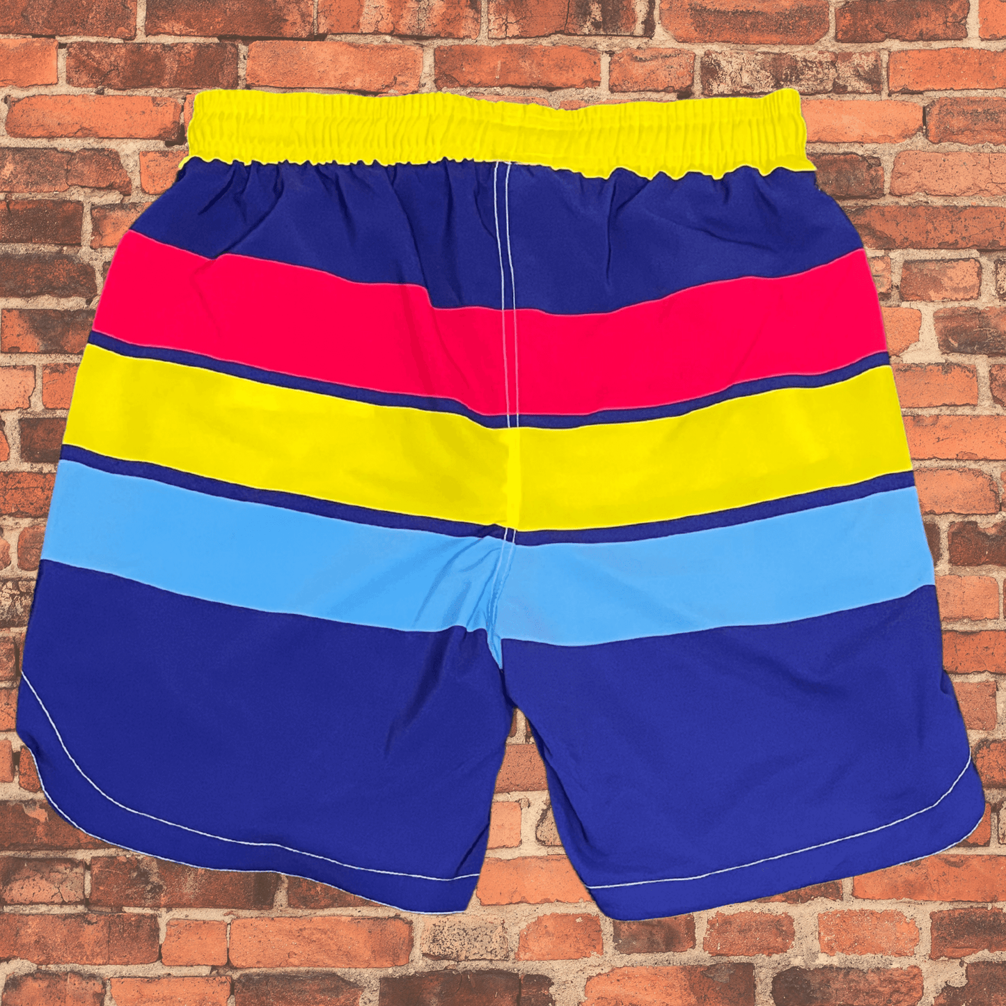 Back view of Toro BJJ Summertime Super Shorts featuring colorful horizontal stripes in red, yellow, blue, and navy with a yellow waistband.