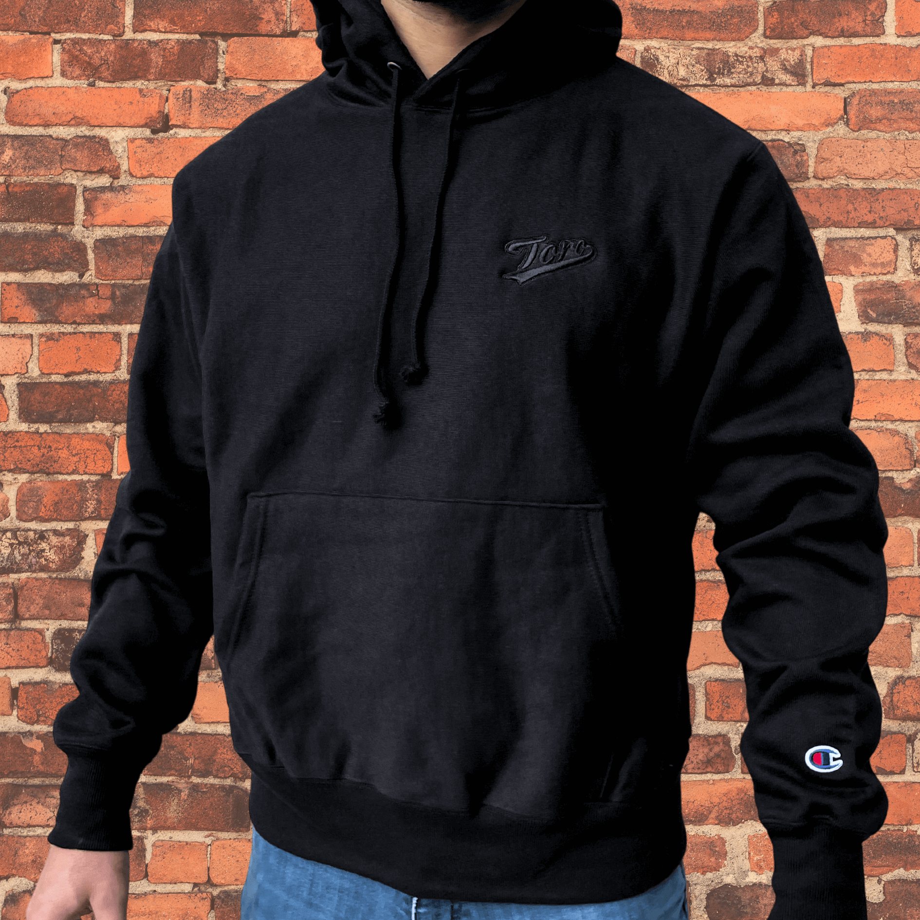 Side view of model wearing Toro x Champion Reverse Weave Hoodie black on black showing fit and cuff details.