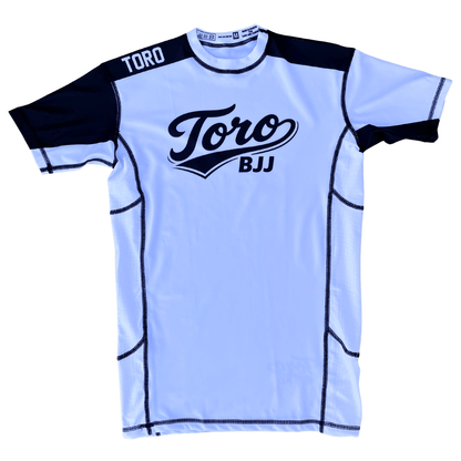 Front view of Toro white belt ranked short-sleeve rash guard with black accents and chest logo