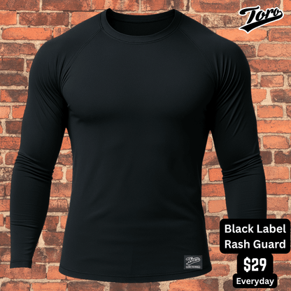 All-black Toro BJJ long sleeve rash guard against brick wall background, premium Black Label NoGi training top.