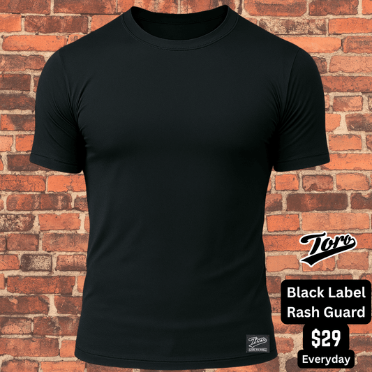 All-black Toro BJJ short sleeve rash guard against brick wall background, Black Label NoGi training top.